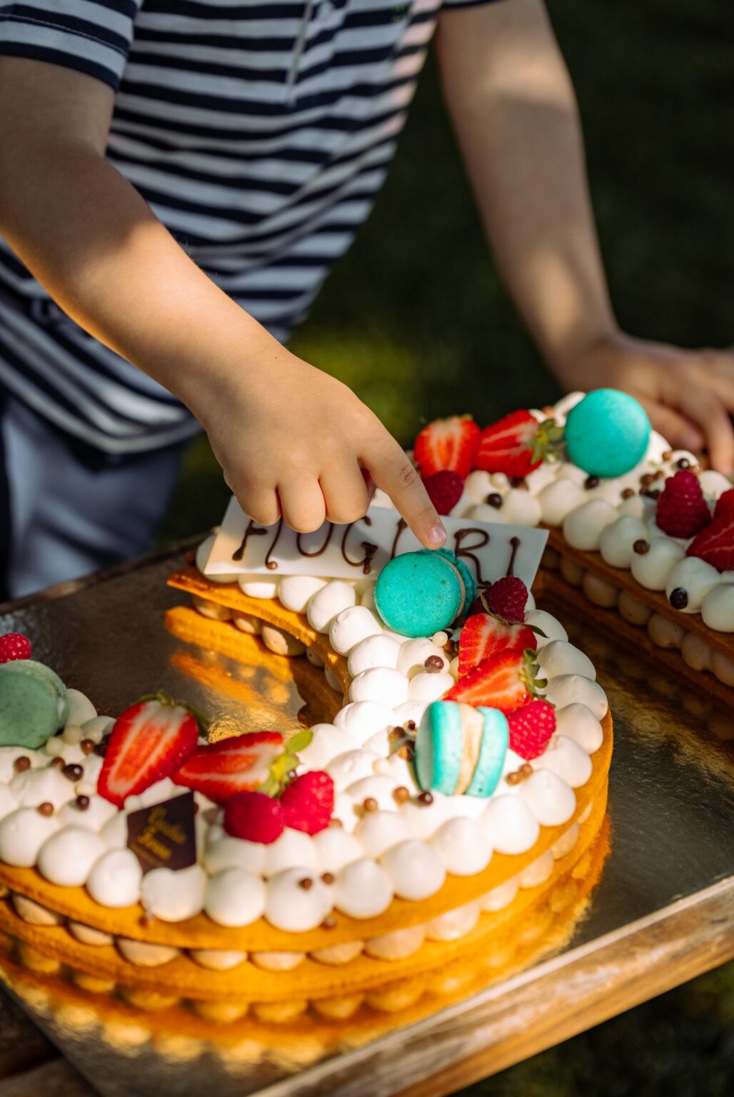 Un bambino tocca la scritta Auguri sulla Creme Tarte a forma di numero