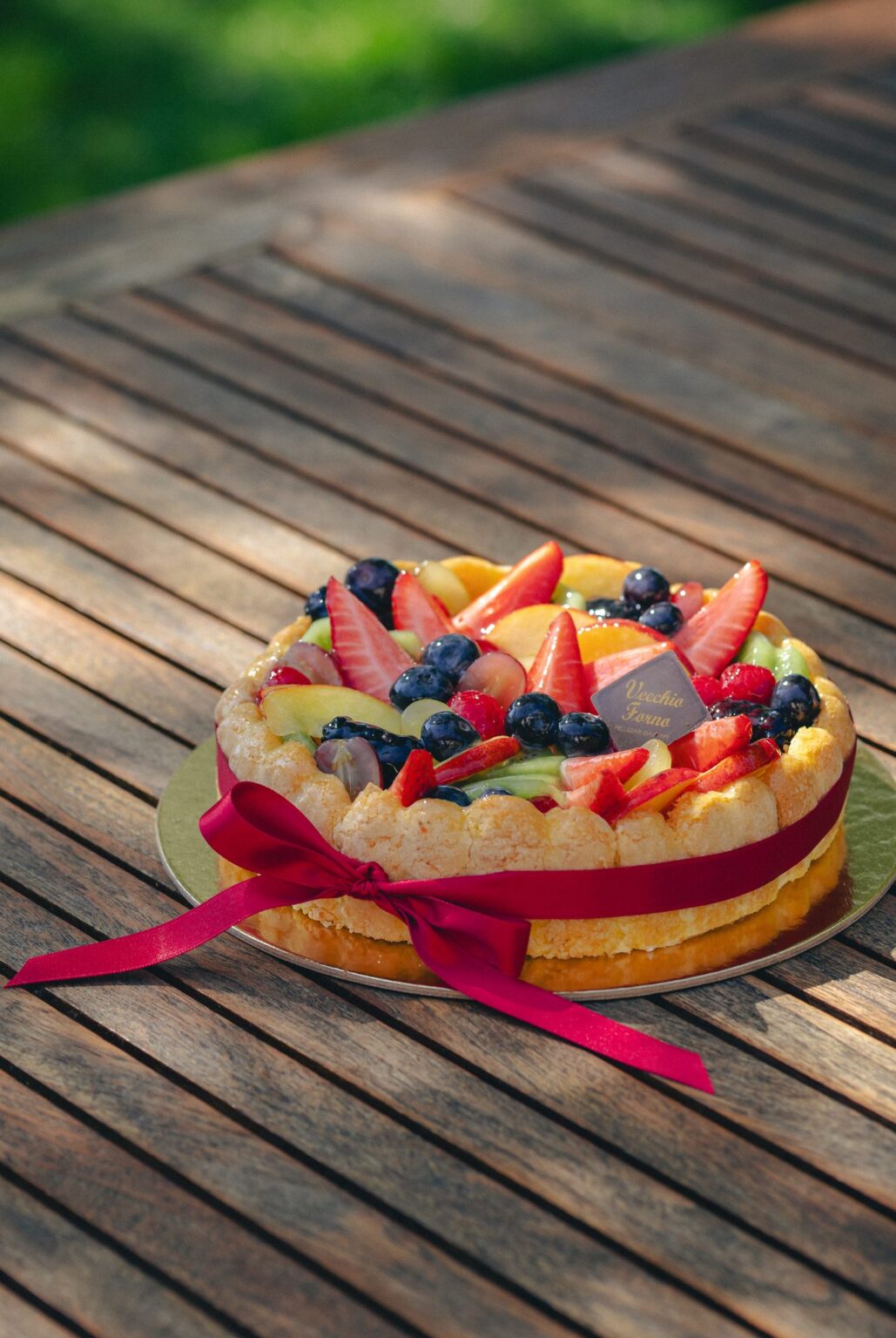 Torta Charlotte intera con cornicione di biscotti e fiocco rosso
