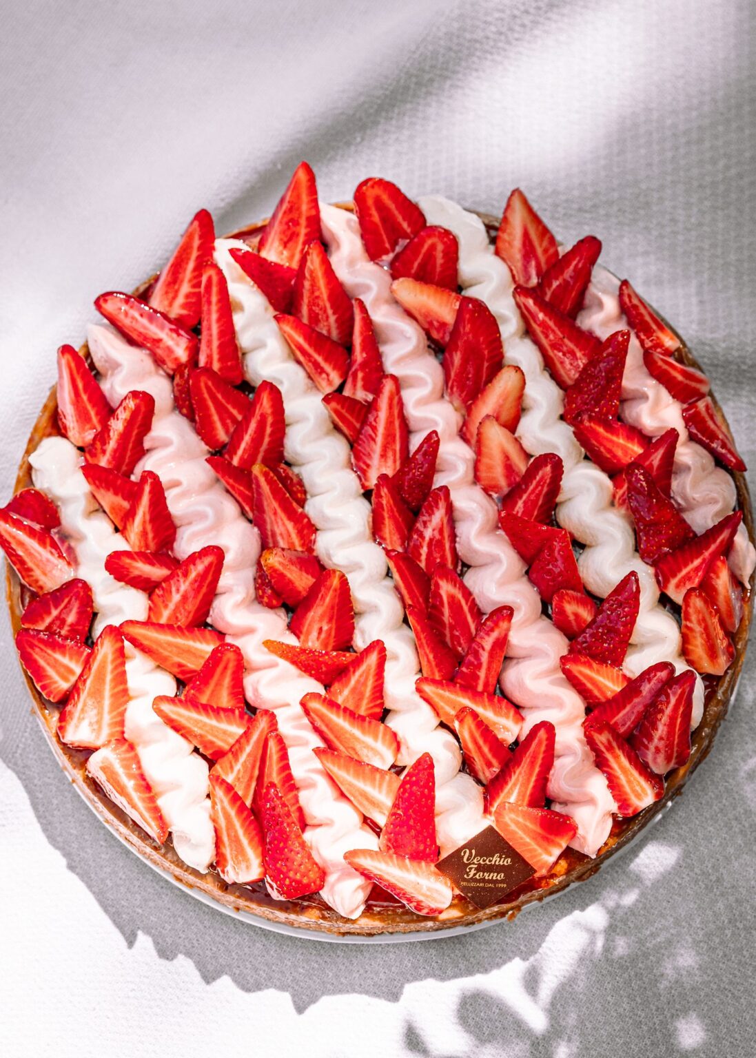 Torta Frangipane vista dall’alto con fragole e ciuffi di cremoso